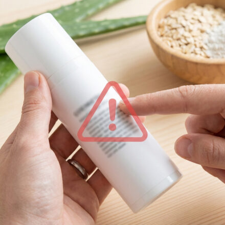 Une main tient un flacon cosmétique blanc avec un panneau d'avertissement rouge. Aloe vera et ingrédients naturels en fond.